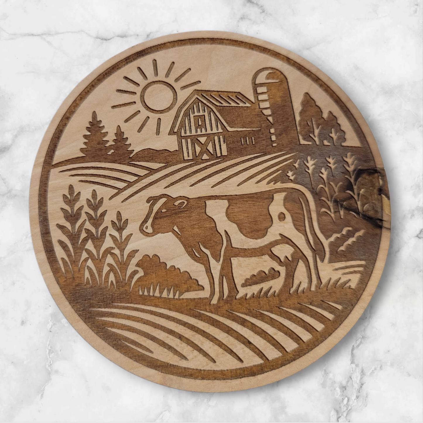 Laser-engraved round wooden magnet featuring a Holstein cow in a rural farm scene with barn, silo, and sun – rustic Wisconsin farmhouse decor by Ellie Joe Design Co.