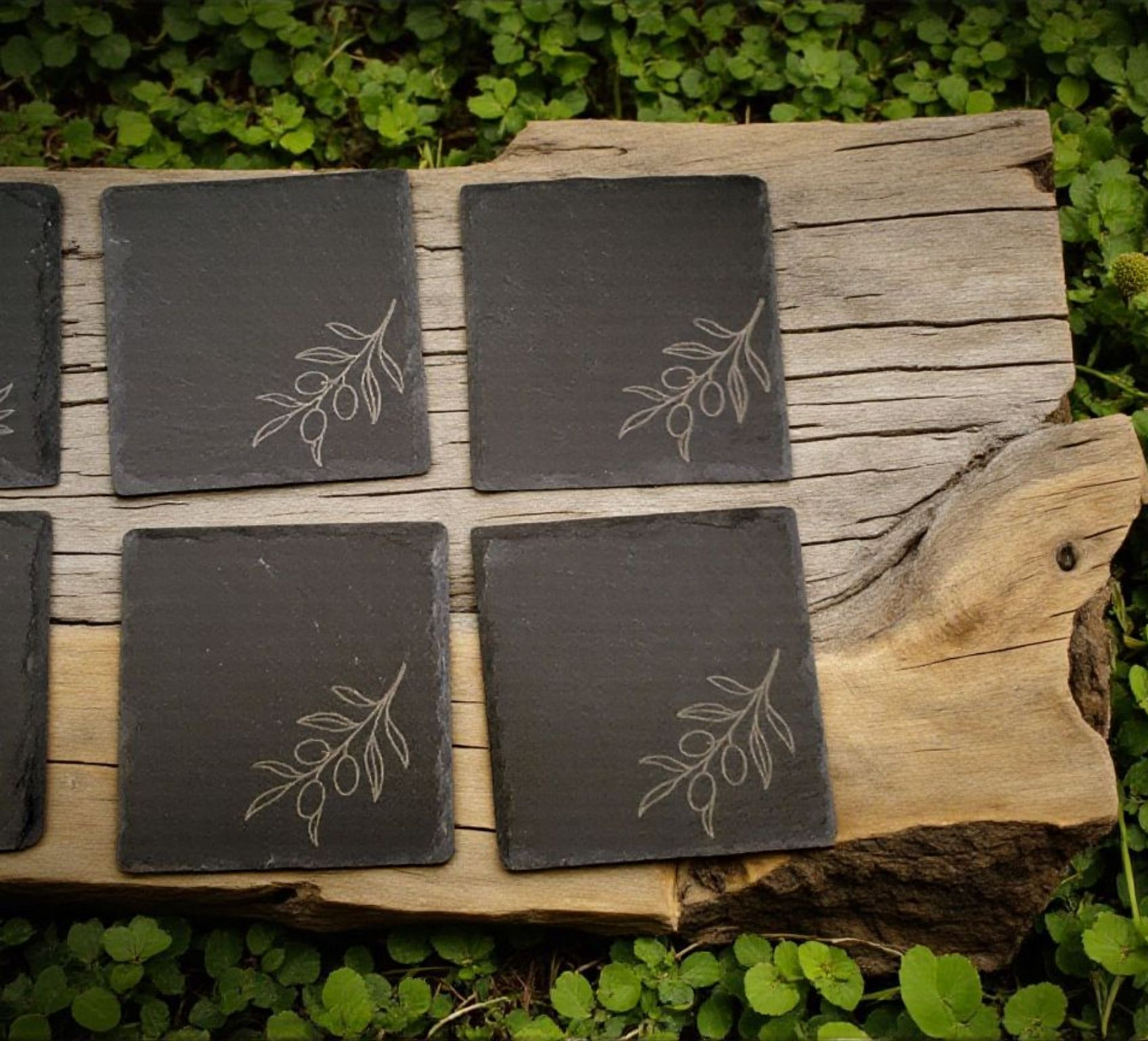 Rustic set of 4 square slate coasters, laser engraved with olive branch sprigs or a wine-and-cheese scene. Natural slate stone with etched line art design, perfect for protecting tables in style.