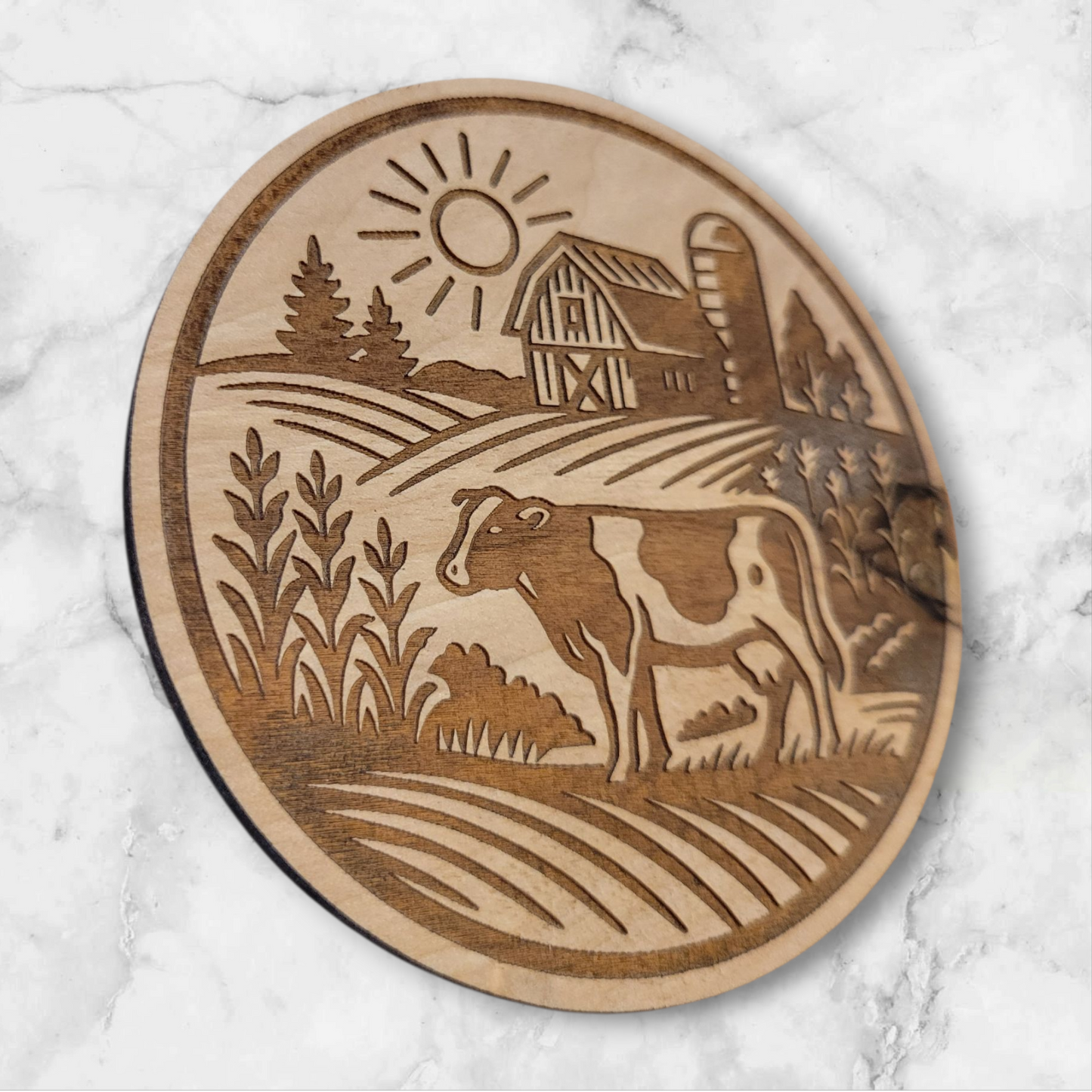 Laser-engraved round wooden magnet featuring a Holstein cow in a rural farm scene with barn, silo, and sun – rustic Wisconsin farmhouse decor by Ellie Joe Design Co.