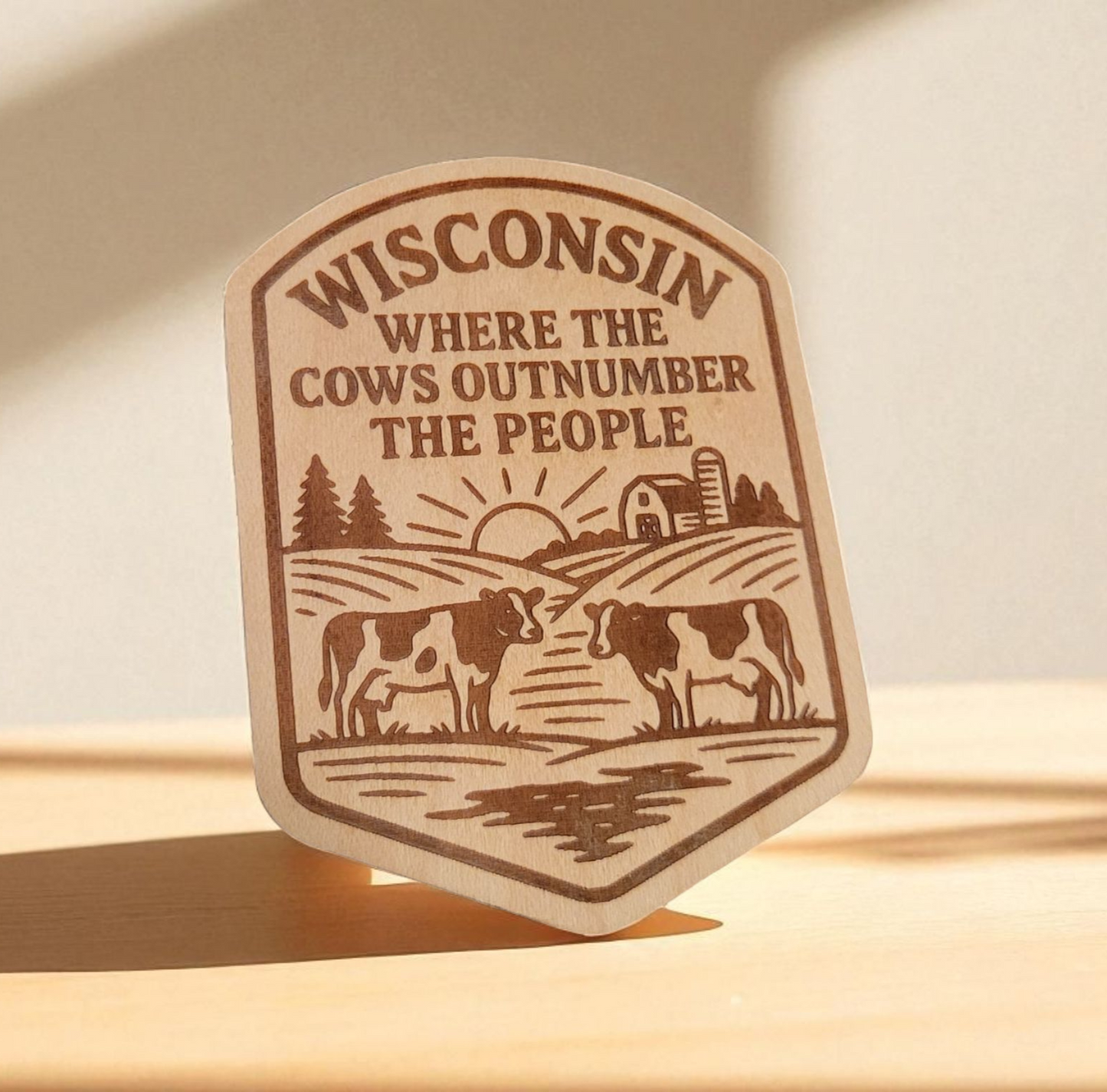 Wood magnet with engraved cows, barn, and the phrase “Wisconsin: Where the Cows Outnumber the People.”