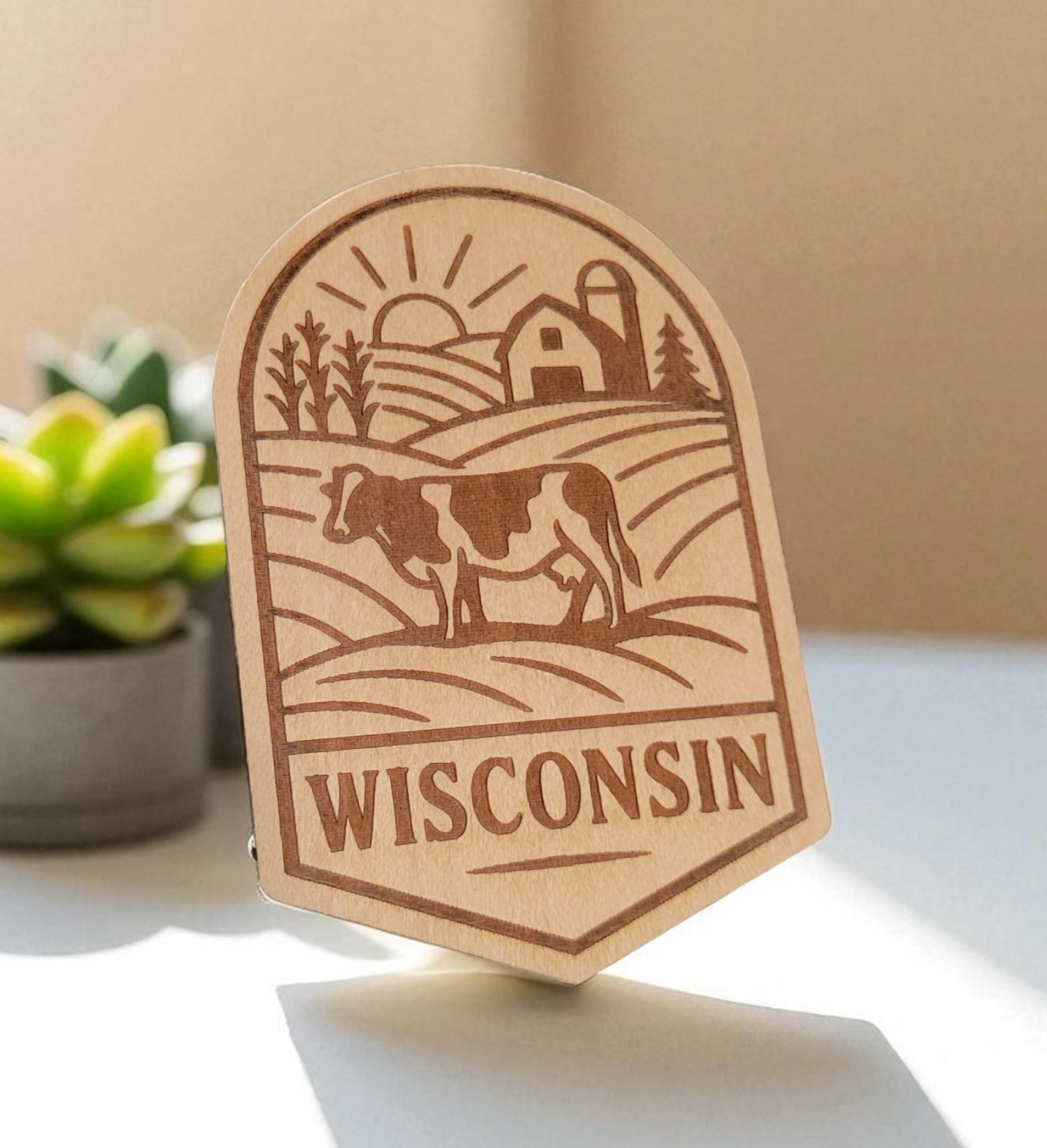 Laser-engraved wood magnet with a cow, barn, cornfield, and rising sun in a scenic Wisconsin farm badge design.