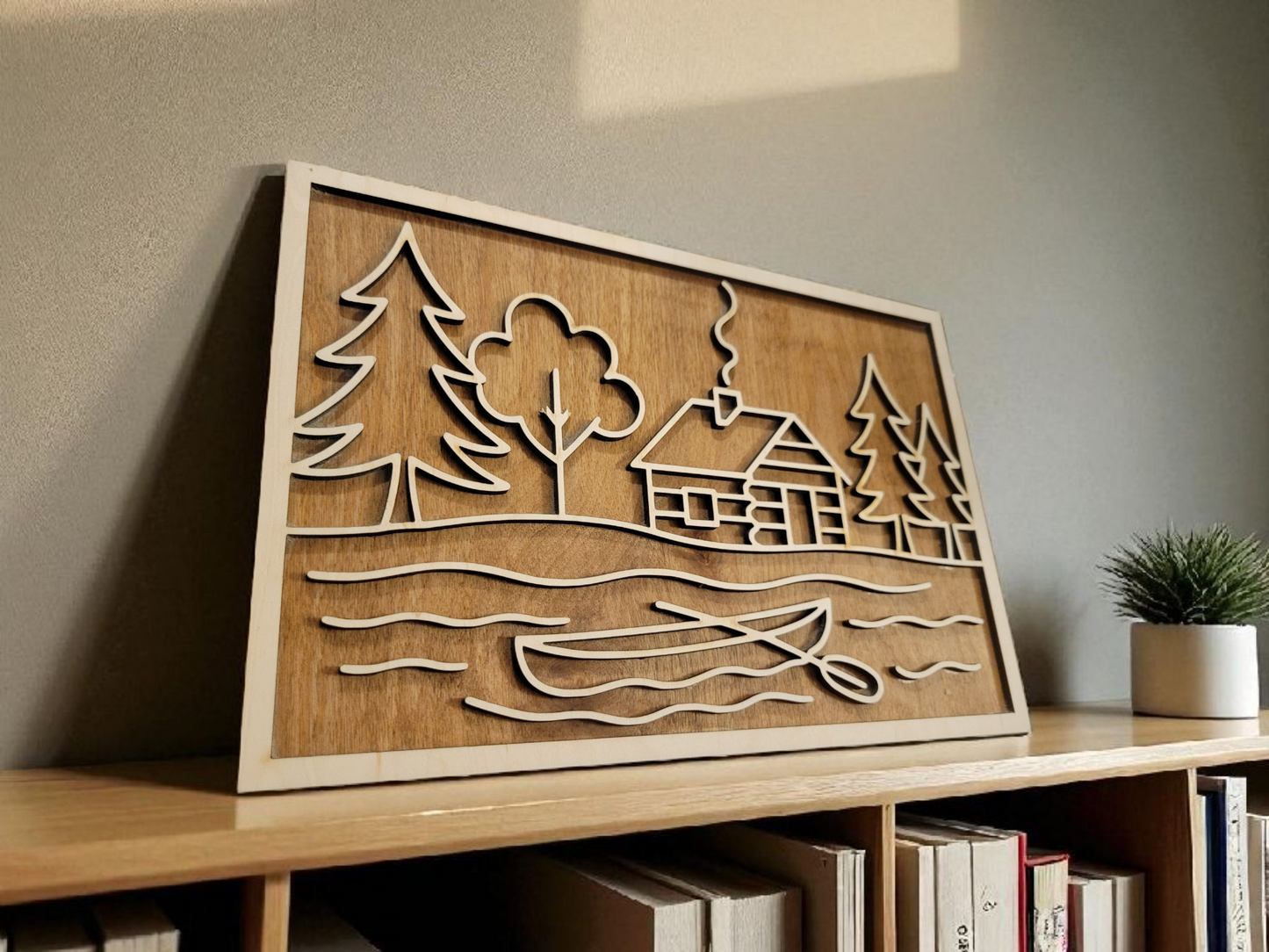 Layered wood sign featuring a rustic cabin, pine trees, and canoe scene — laser cut from multiple layers of natural wood, perfect for lake house or cabin decor.