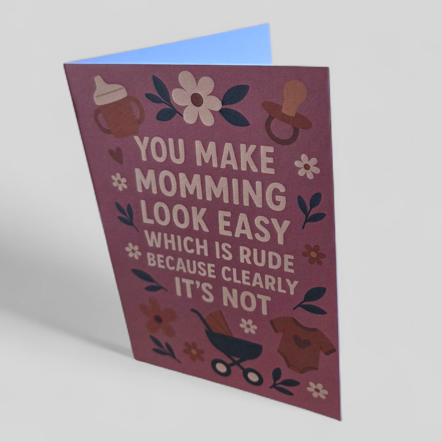 Greeting card reading ‘You make momming look easy which is rude because clearly it’s not’ with pink background and floral accents.