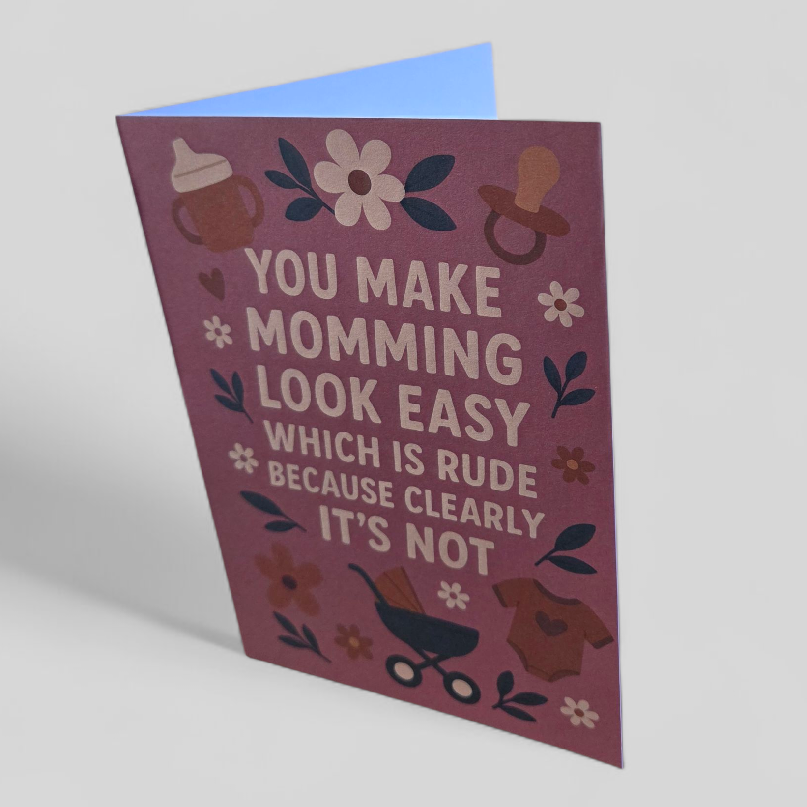 Greeting card reading ‘You make momming look easy which is rude because clearly it’s not’ with pink background and floral accents.