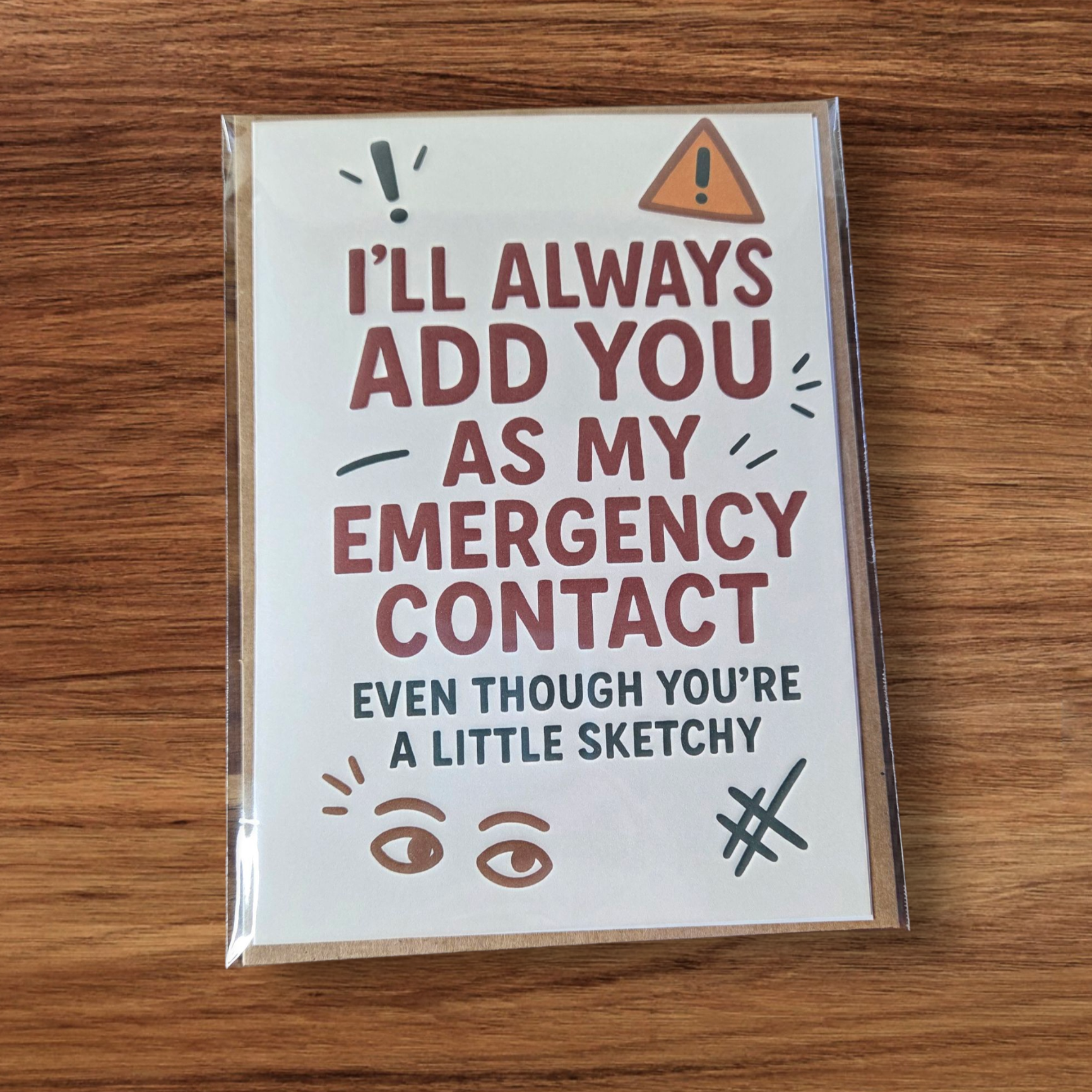 Greeting card reading ‘I’ll Always Add You As My Emergency Contact Even Though You’re A Little Sketchy’ with playful icons.