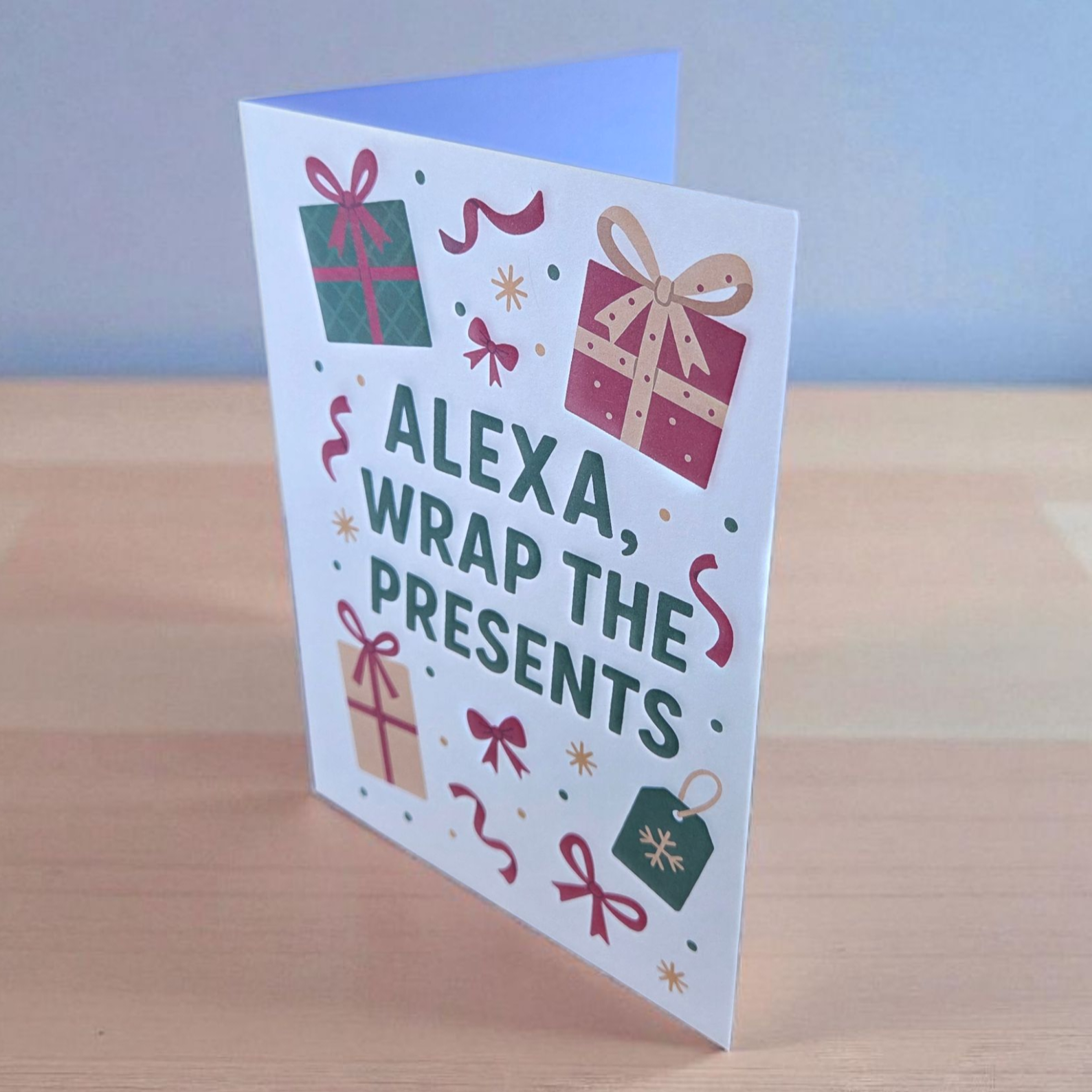Funny Christmas greeting card reading ‘Alexa, Wrap the Presents’ surrounded by wrapped gift illustrations.