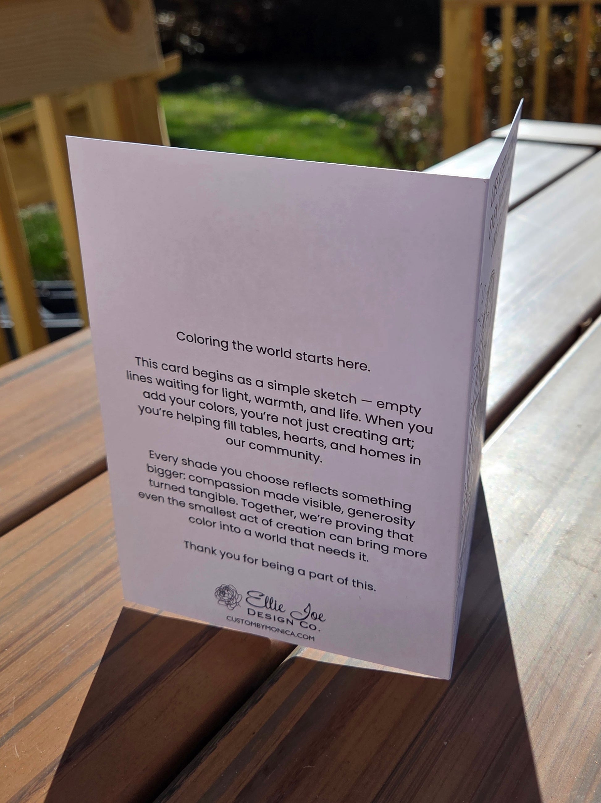 Back of greeting card featuring Ellie Joe Design Co. message about coloring the world and giving back to the local food bank.