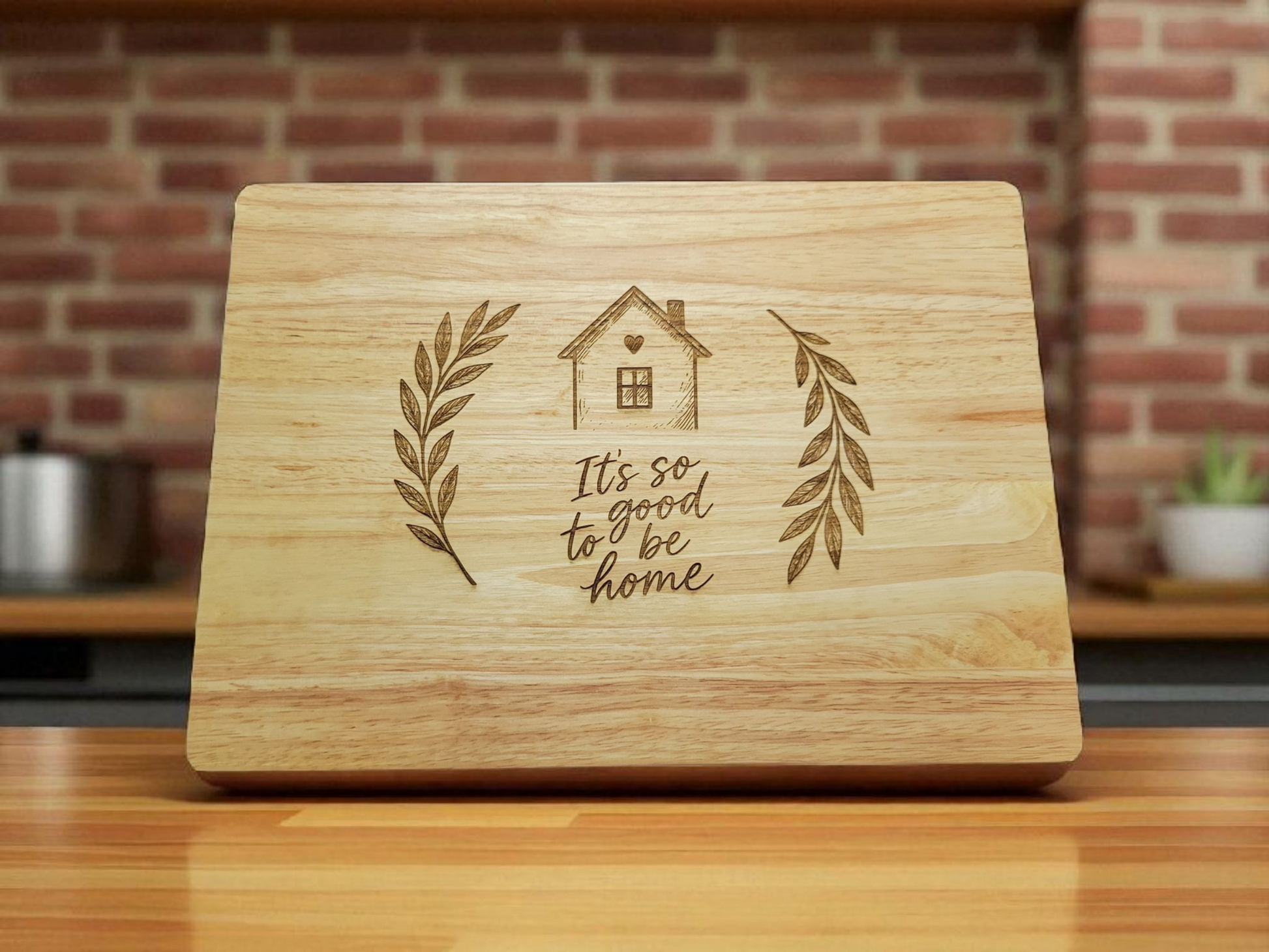 Engraved wooden cutting board with house and laurel design and the phrase It’s so good to be home – rustic farmhouse kitchen décor and gift