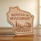 State-shaped wood magnet engraved with “Rooted in Wisconsin” and a farm scene with trees and barn.