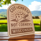 Wood magnet engraved with cheese wedge, knife, and the phrase “Cut the Cheese, Not Corners – Wisconsin.”