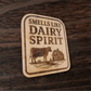 Laser-engraved wood magnet with cow and barn design, captioned “Smells Like Dairy Spirit”