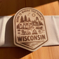 Wood magnet engraved with camper, pine trees, and fire pit, and the phrase “Home is where you park it – Wisconsin.”