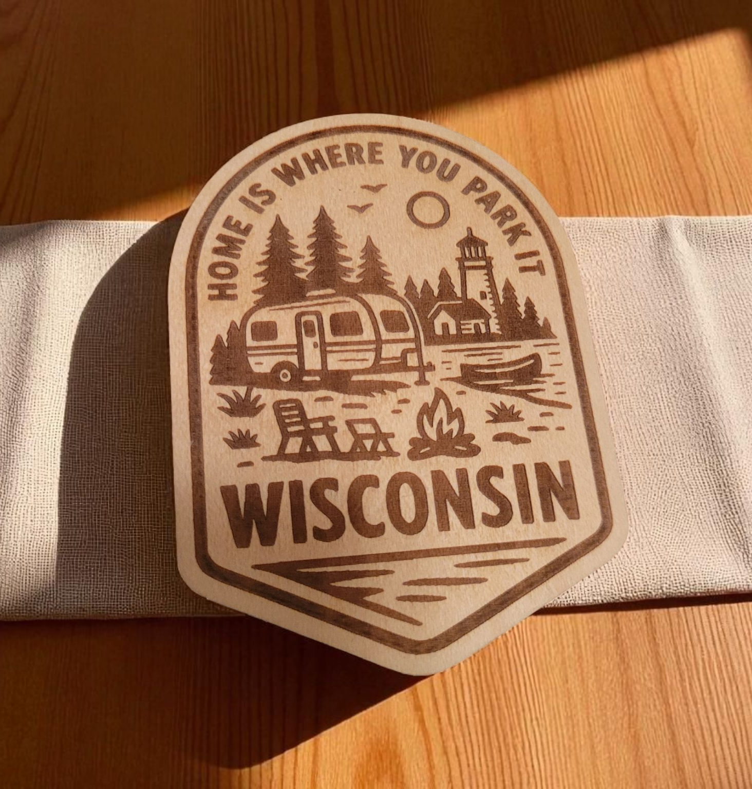 Wood magnet engraved with camper, pine trees, and fire pit, and the phrase “Home is where you park it – Wisconsin.”