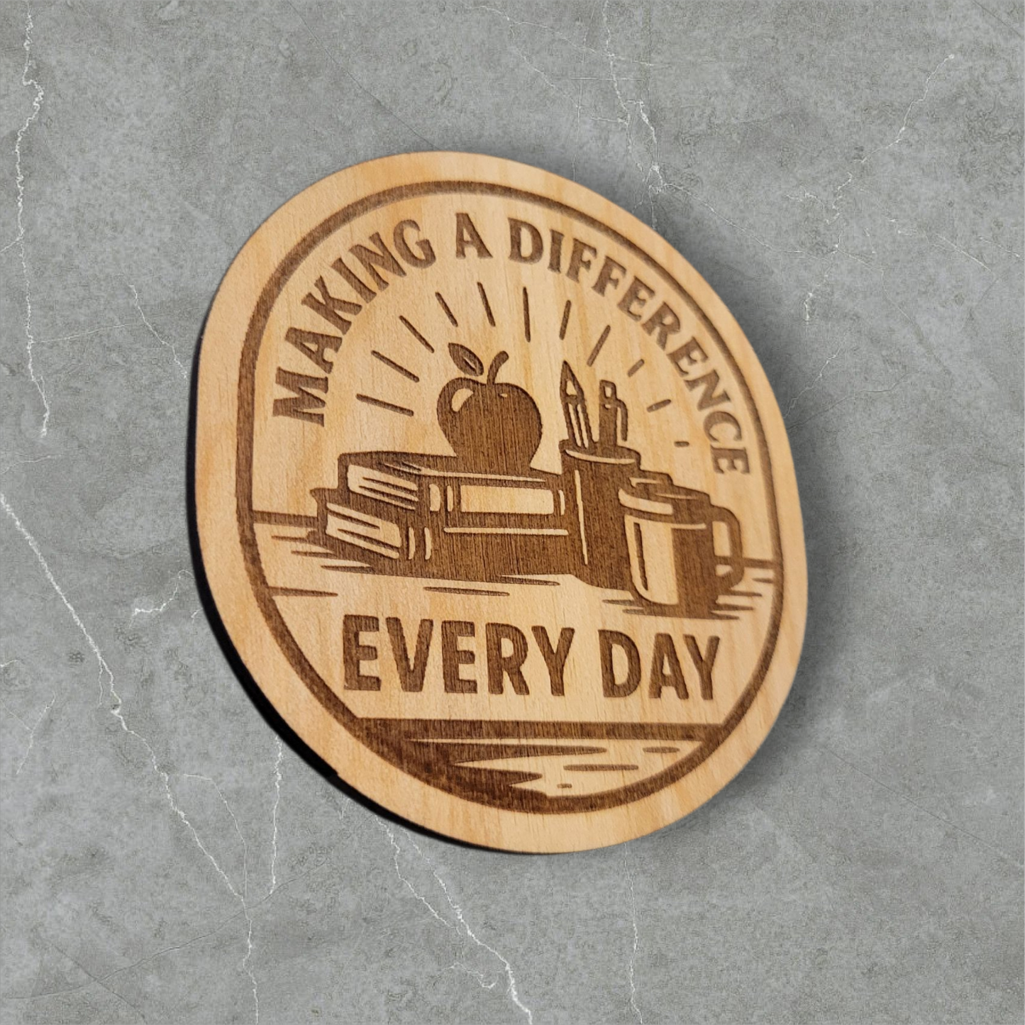 Laser engraved wood magnet with the phrase “Making a Difference Every Day” featuring an apple, books, pencils, and coffee mug