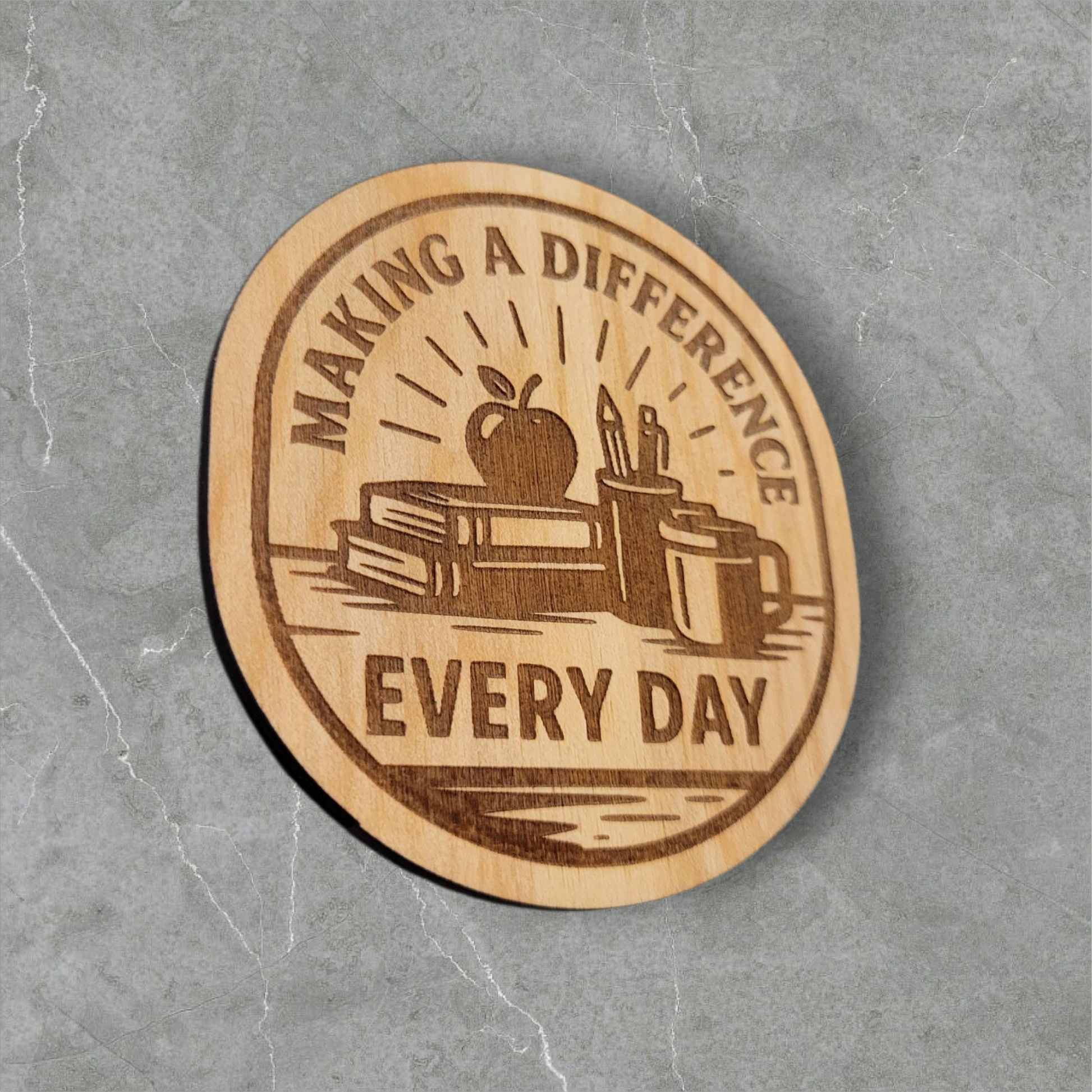 Laser engraved wood magnet with the phrase “Making a Difference Every Day” featuring an apple, books, pencils, and coffee mug