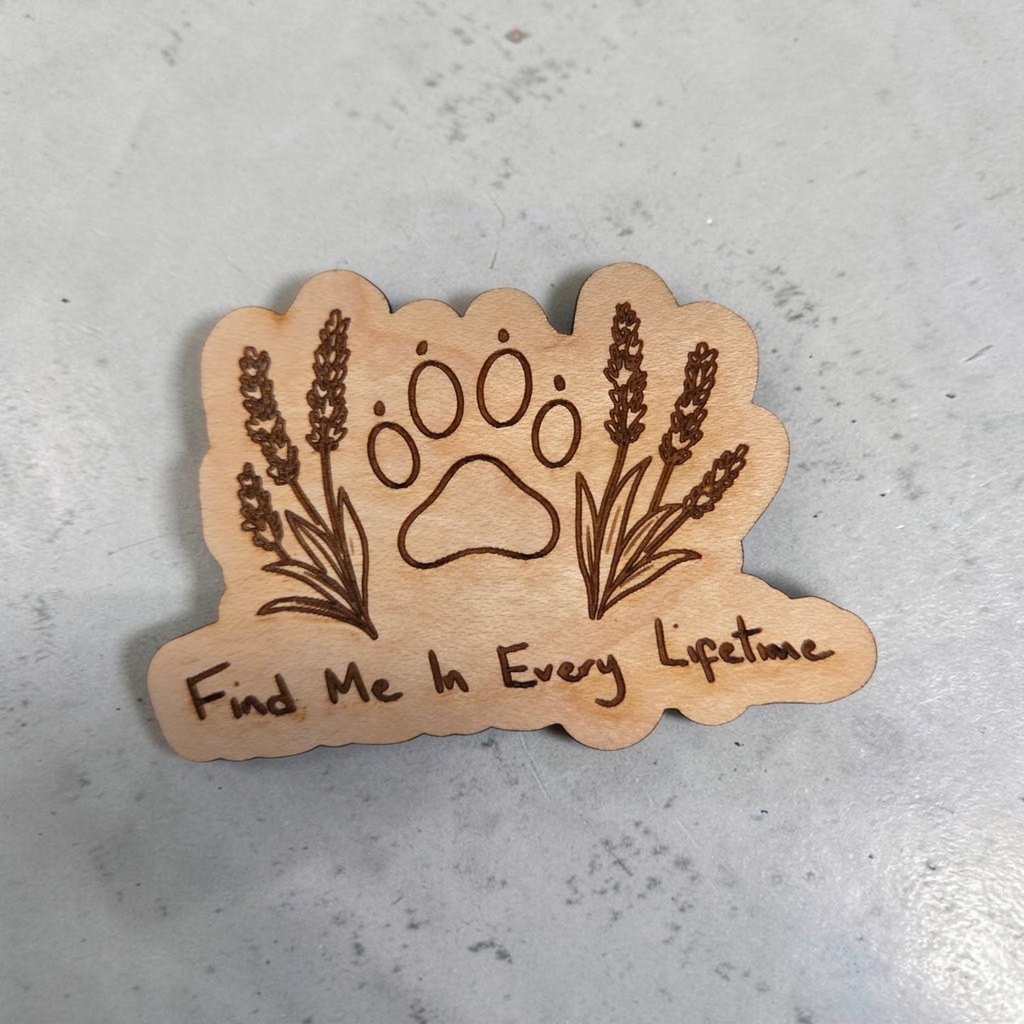 Handcrafted natural wood magnet engraved with a paw print, botanical sprigs, and the phrase “Find Me In Every Lifetime,” photographed on a neutral gray background.