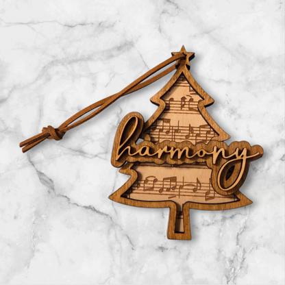Wooden Christmas tree ornament engraved with sheet music and the word ‘harmony.