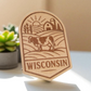 Laser-engraved wood magnet with a cow, barn, cornfield, and rising sun in a scenic Wisconsin farm badge design.
