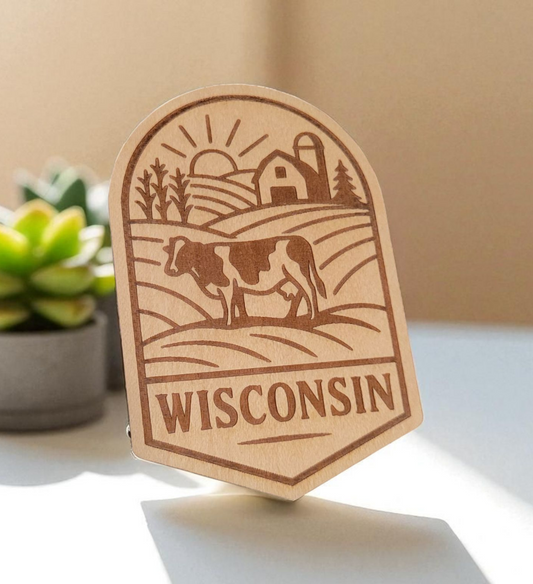 Laser-engraved wood magnet with a cow, barn, cornfield, and rising sun in a scenic Wisconsin farm badge design.